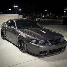 a silver sports car parked in a parking lot at night with street lights behind it