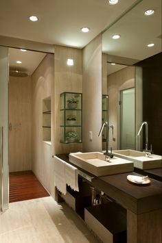 a bathroom with two sinks and mirrors in the middle, along with lights above them