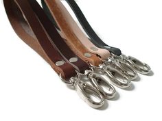 four pairs of scissors are lined up in a row on a white background with black and brown leather straps