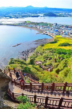 people are walking up and down the wooden stairs near the water with mountains in the background