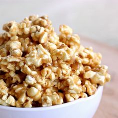 a white bowl filled with popcorn on top of a wooden table