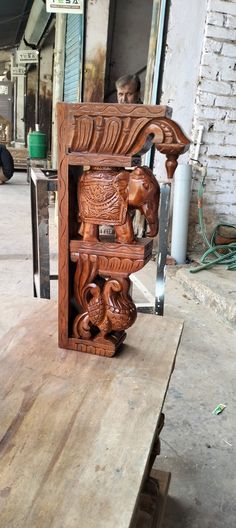 an intricate carved wooden shelf with carvings on the front and sides, sitting on top of a piece of wood