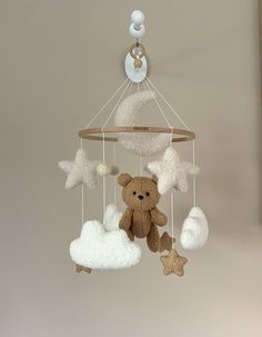 a teddy bear hanging from a mobile in the shape of clouds and stars with a star on top