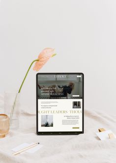 a laptop computer sitting on top of a table next to a vase filled with flowers