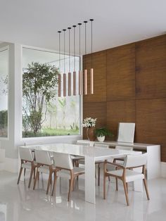 a modern dining room with white chairs and wood paneling