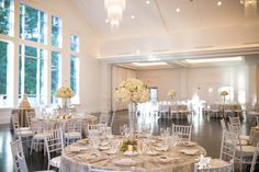 the tables are set up for a formal function with flowers in vases and place settings