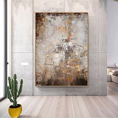 an abstract painting hangs on the wall next to a potted cactus in a modern living room