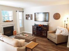 a living room filled with furniture and a flat screen tv mounted on the wall above a fireplace