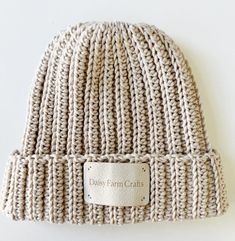 a white knitted hat with a label on the front that says daisy farm crafts