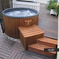 a hot tub sitting on top of a wooden deck next to a building and stairs