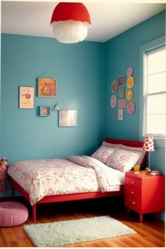 a bedroom with blue walls and red bedding, white rugs and pictures on the wall