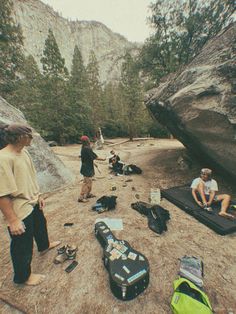 several people are camping in the mountains with their luggage and backpacks on the ground