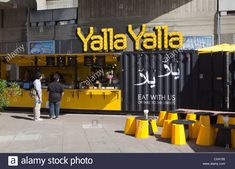 people standing in front of a yellow and black food stand