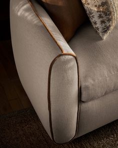 a close up of a couch with pillows on top of it and a wooden floor