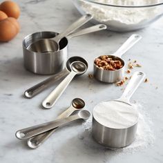 measuring spoons and measuring cups on a marble countertop with eggs in the background