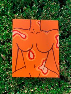 an orange piece of art sitting on top of green bushes