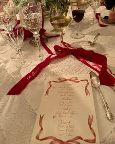 a table set with wine glasses, silverware and a menu on top of it