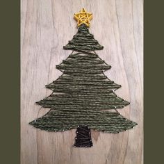 a christmas tree made out of yarn on top of a wooden table with a star hanging from it