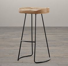 a wooden stool sitting on top of a hard wood floor next to a white wall