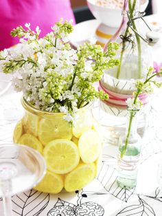 a vase filled with lemons and flowers on top of a table