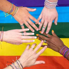 several hands with different colored nail polish on them and one holding the other's hand