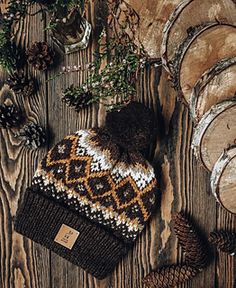 a knitted hat sitting on top of a wooden table next to pine cones and other items