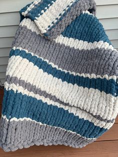 a blue and gray blanket sitting on top of a wooden floor next to a wall