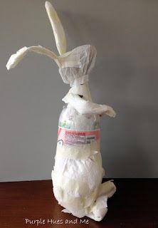 a stuffed rabbit sitting on its hind legs holding a bag of toilet paper in it's mouth