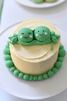 two peas sitting on top of a cake next to other cakes and cupcakes