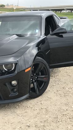 a black chevrolet camaro is parked in the dirt