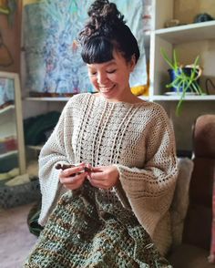 a woman sitting on the floor holding a cell phone in her hands and smiling at the camera