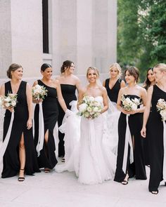 a group of women standing next to each other wearing black dresses and holding bouquets