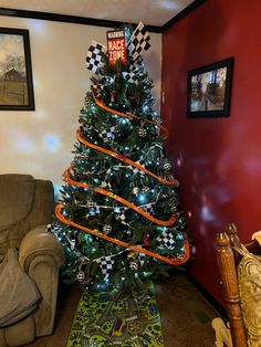 a christmas tree decorated with race flags and lights in a living room next to a couch