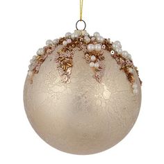 an ornament with pearls and gold trimmings hanging from a chain on a white background