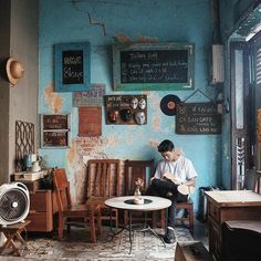 a man sitting on a chair in front of a blue wall with writing on it