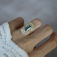 Read about our payment plans before proceeding. A ring that beautifully captures the ethereal allure of vintage design with a touch of celestial inspiration. This exquisite piece features a captivating emerald-cut London Blue Topaz at its center, radiating a deep, mesmerizing blue reminiscent of twilight skies. Surrounding the gemstone is a cluster of sparkling diamonds, each one set in a delicate, vintage-inspired gold setting that evokes the timeless beauty of heirloom jewelry. The intricate details of the gold filigree, combined with the serene blue of the topaz, create a sense of floating among the clouds, making this ring a perfect choice for those who dream of vintage charm with a modern twist. All orders come in our Tippy Taste ring box. This ring is handmade and designed in NYC. 14 Celestial Inspiration, Among The Clouds, Heirloom Jewelry, Twilight Sky, Celestial Wedding, Heirlooms Jewelry, Gold Filigree, London Blue Topaz, London Blue