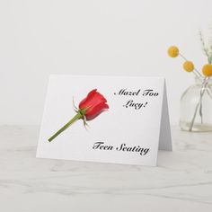 a red rose sitting on top of a table next to a vase filled with flowers