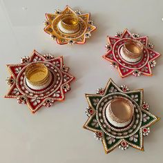 four decorative objects are arranged on a white surface with gold, red and green accents