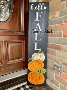 a wooden sign that says hello fall and has pumpkins on it in front of a door