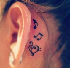 a woman's ear with musical notes and heart tattoo on her left behind the ear