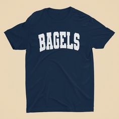 Let's toast to everyone's favorite breakfast with our Unisex 'BAGELS' T-Shirt! This tee is a delightful choice for foodies, brunch lovers, bakery fans, and anyone who can't resist a well-toasted bagel. This unique tee is a fun and appetizing way to show your love for this beloved breakfast staple. Whether you're enjoying brunch, visiting a bakery, or just hanging out, this T-shirt is a fantastic addition to your casual wear. With its universal appeal, it also makes a perfect gift for your bagel- Funny Text Crew Neck T-shirt For College, Short Sleeve Screen Print T-shirt For Brunch, Short Sleeve T-shirt With Screen Print For Brunch, Cotton T-shirt With Letter Print For Brunch, Graphic Tee With Letter Print For Brunch, Casual Screen Print T-shirt For Brunch, Screen Print Crew Neck T-shirt For Brunch, Crew Neck T-shirt With Screen Print For Brunch, Casual T-shirt With Funny Text For Game Day