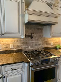 a stove top oven sitting inside of a kitchen next to white cabinets and counter tops