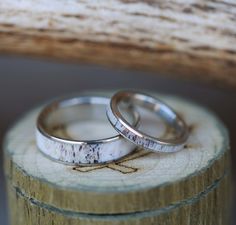 two wedding rings sitting on top of a piece of wood