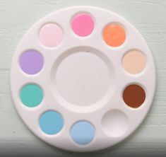 a white plate with many different colored paint colors on it's side and the top half of its circle