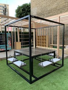 an outdoor play area with swings and benches on artificial grass in front of a building