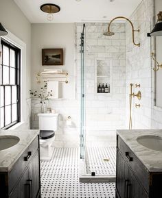 a bathroom with two sinks, a toilet and a walk in shower next to a window