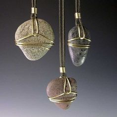 two stone pendants hanging from a chain on a gray background, one with wire wrapped around it