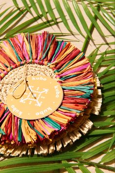 a paper plate with a clock on it sitting in the palm tree leaves that has been decorated