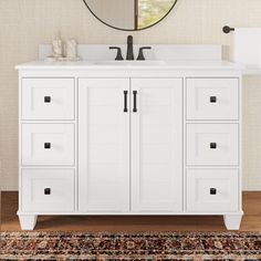 a bathroom vanity with white drawers and a round mirror