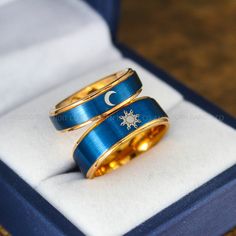 two gold and blue wedding rings with the moon and star on them in a box